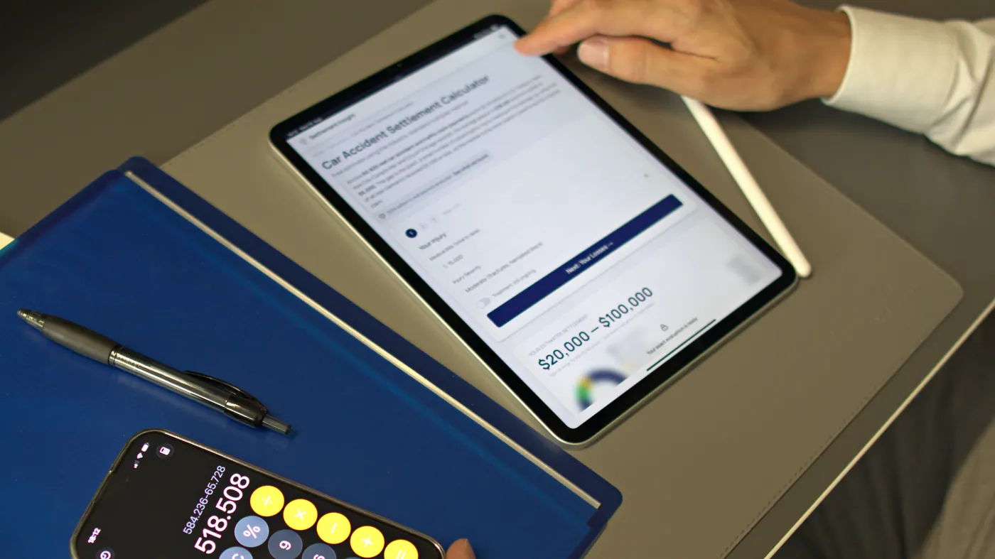 A phone calculator next to a tablet showing the Settlement Insight car accident settlement calculator